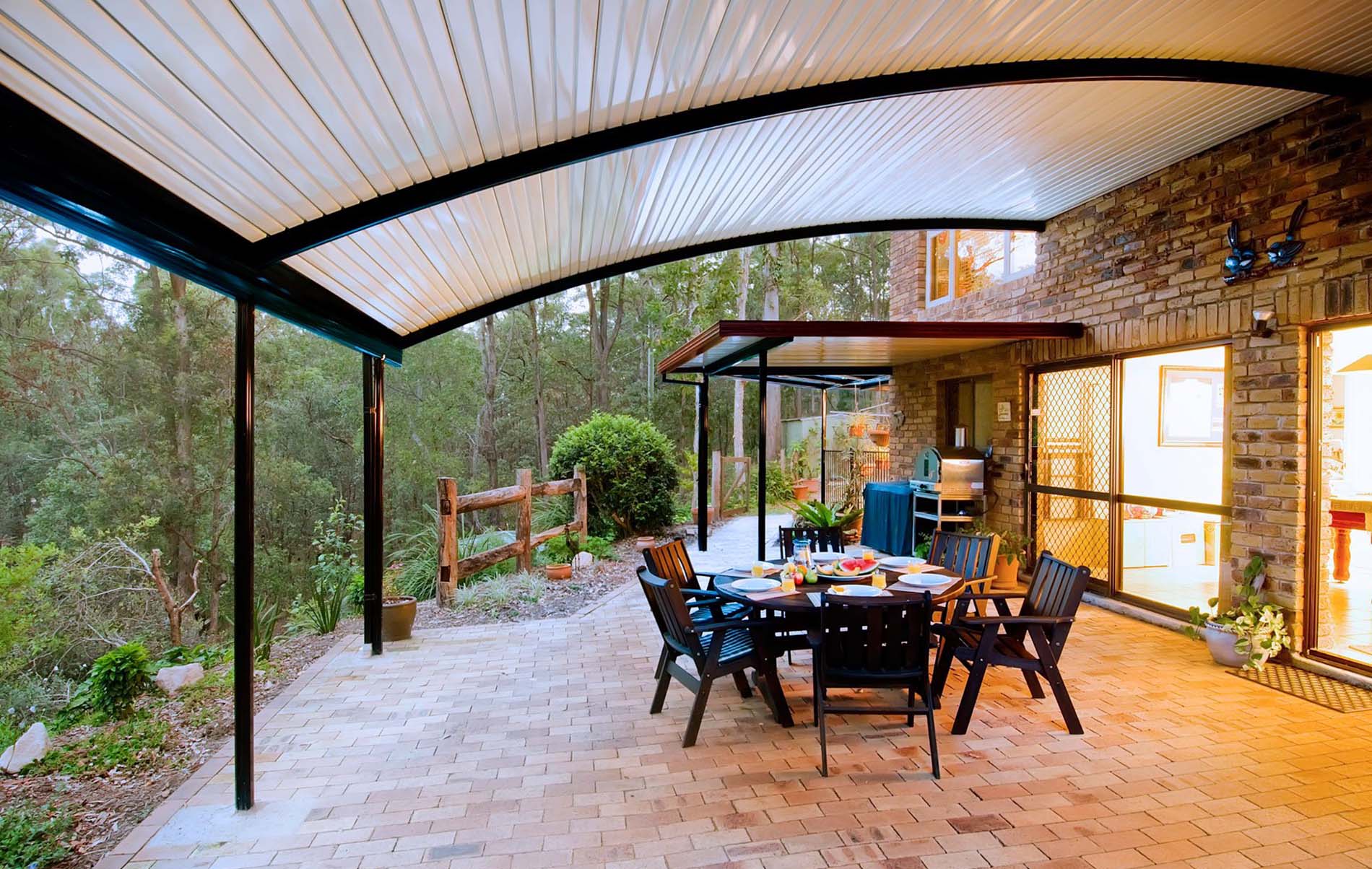 Contemporary curved patio with high gloss steel roof and modern furniture
