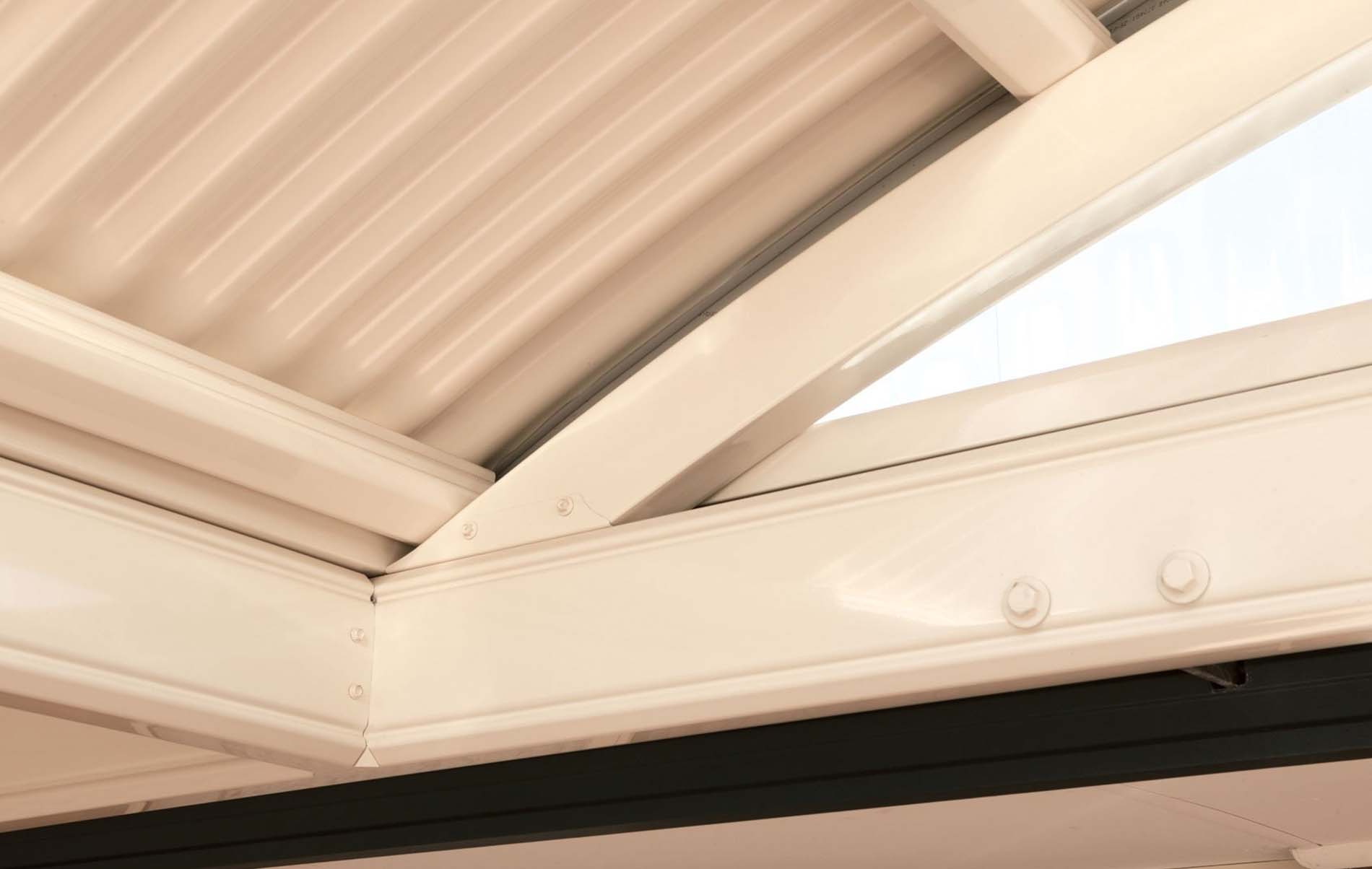 Close-up of curved patio roof structure showing steel beams and corrugated roofing panel