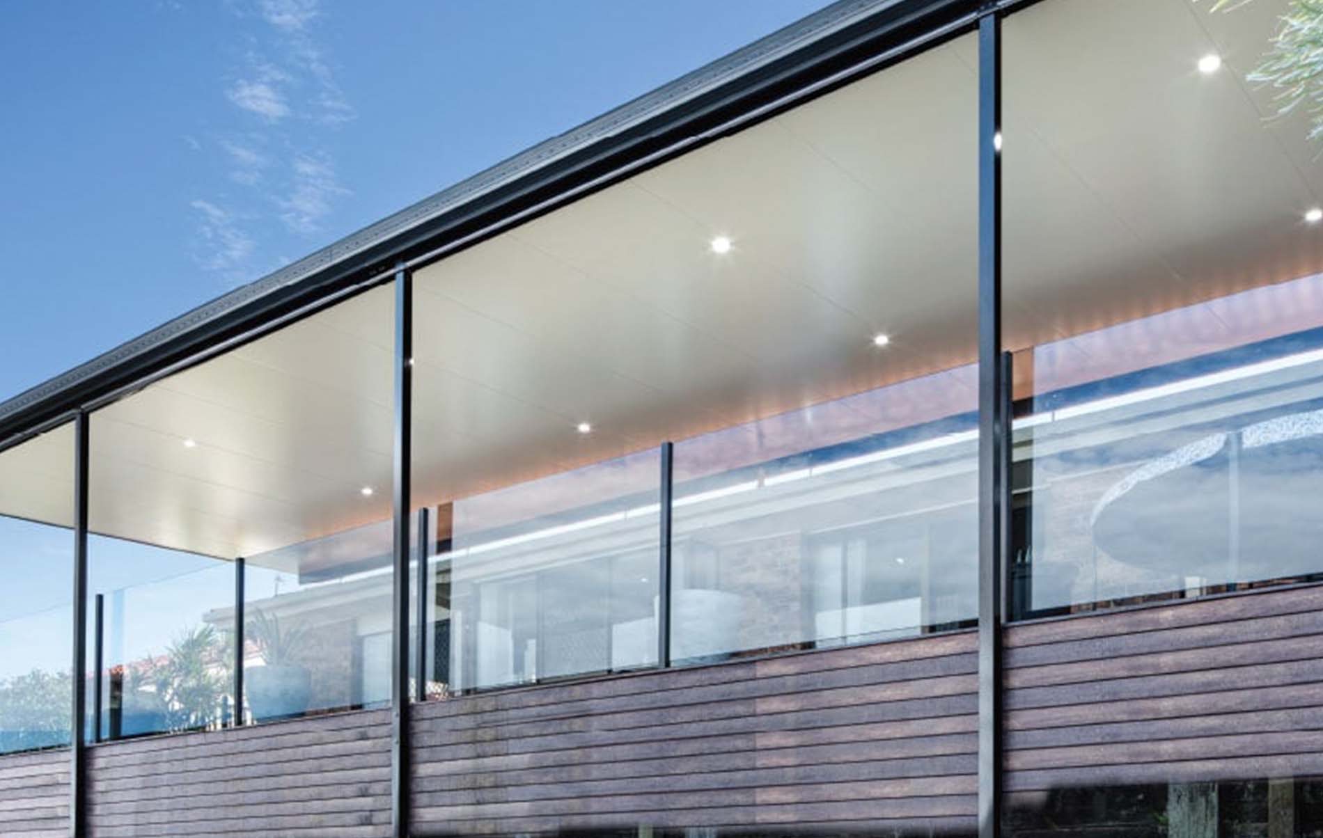 Stylish outdoor patio featuring Stratco Cooldek insulated flat roof panels with integrated lighting and ceiling fans.