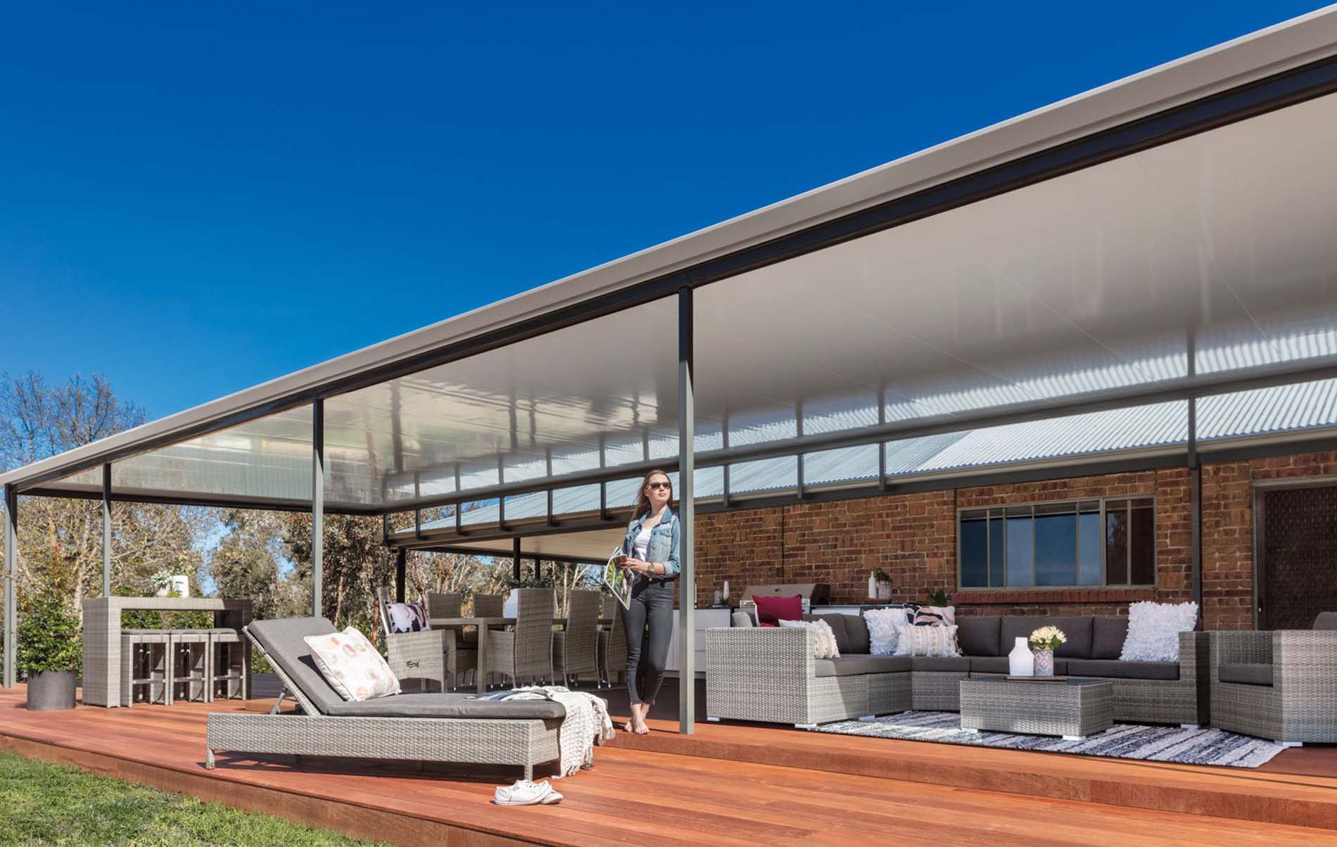 Spacious outdoor patio featuring Stratco Cooldek insulated flat roof panels, seamlessly integrated with modern outdoor furniture and ambient lighting, creating an inviting entertainment area.
