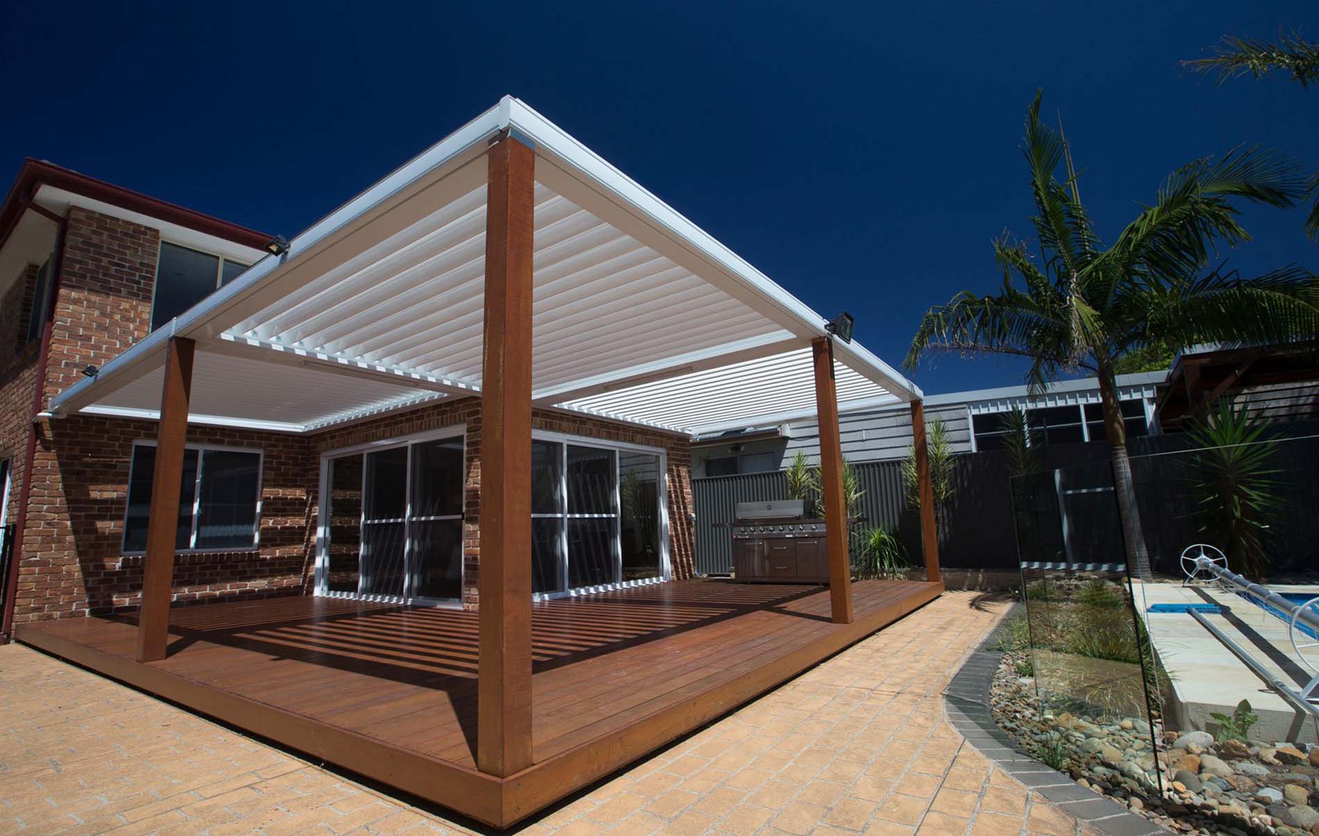Outdoor louvre patio with timber-look frame, adjustable slats overhead and garden edge seating
