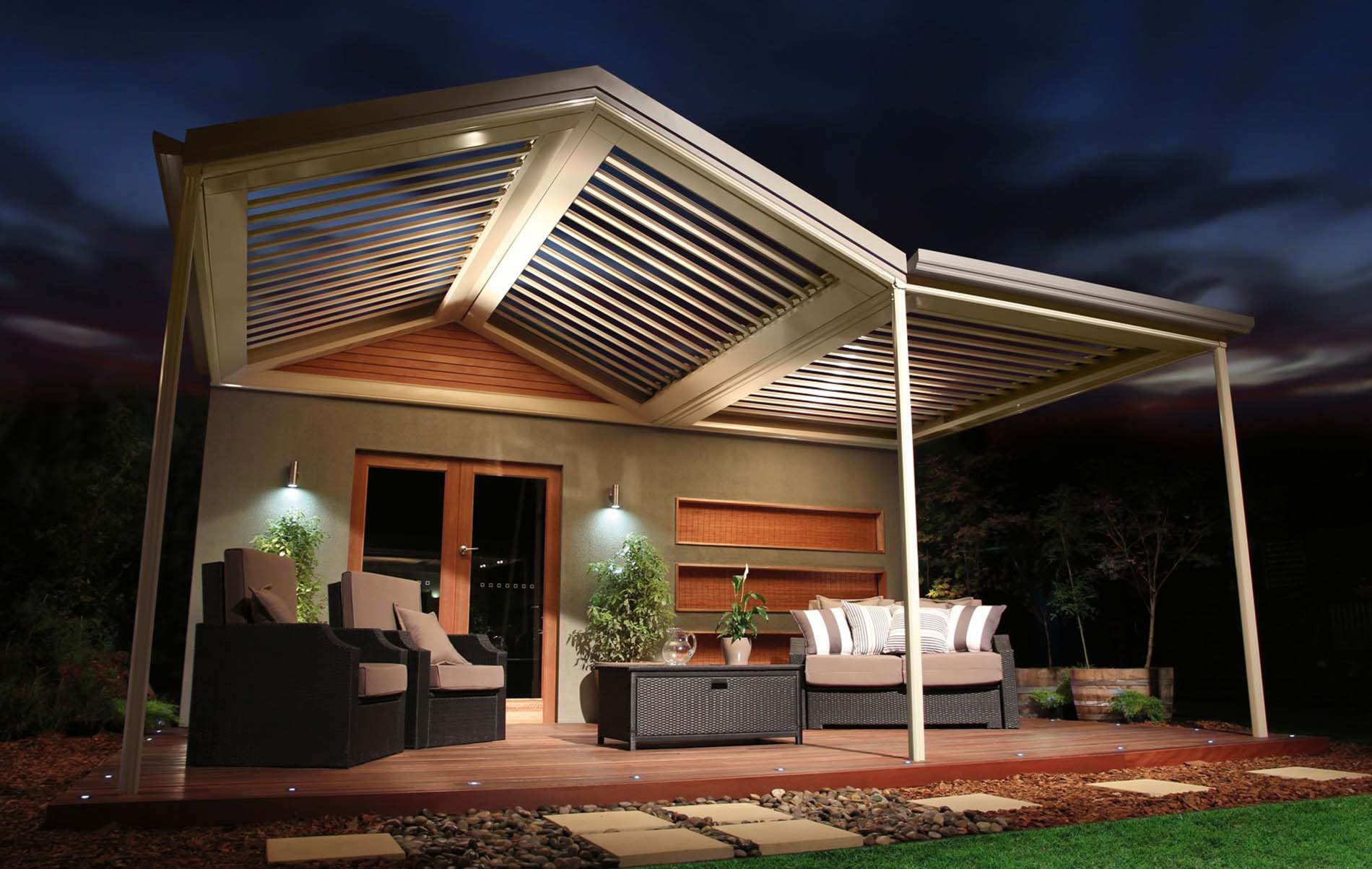 Evening view of adjustable louvre patio roof over outdoor lounge area with soft lighting