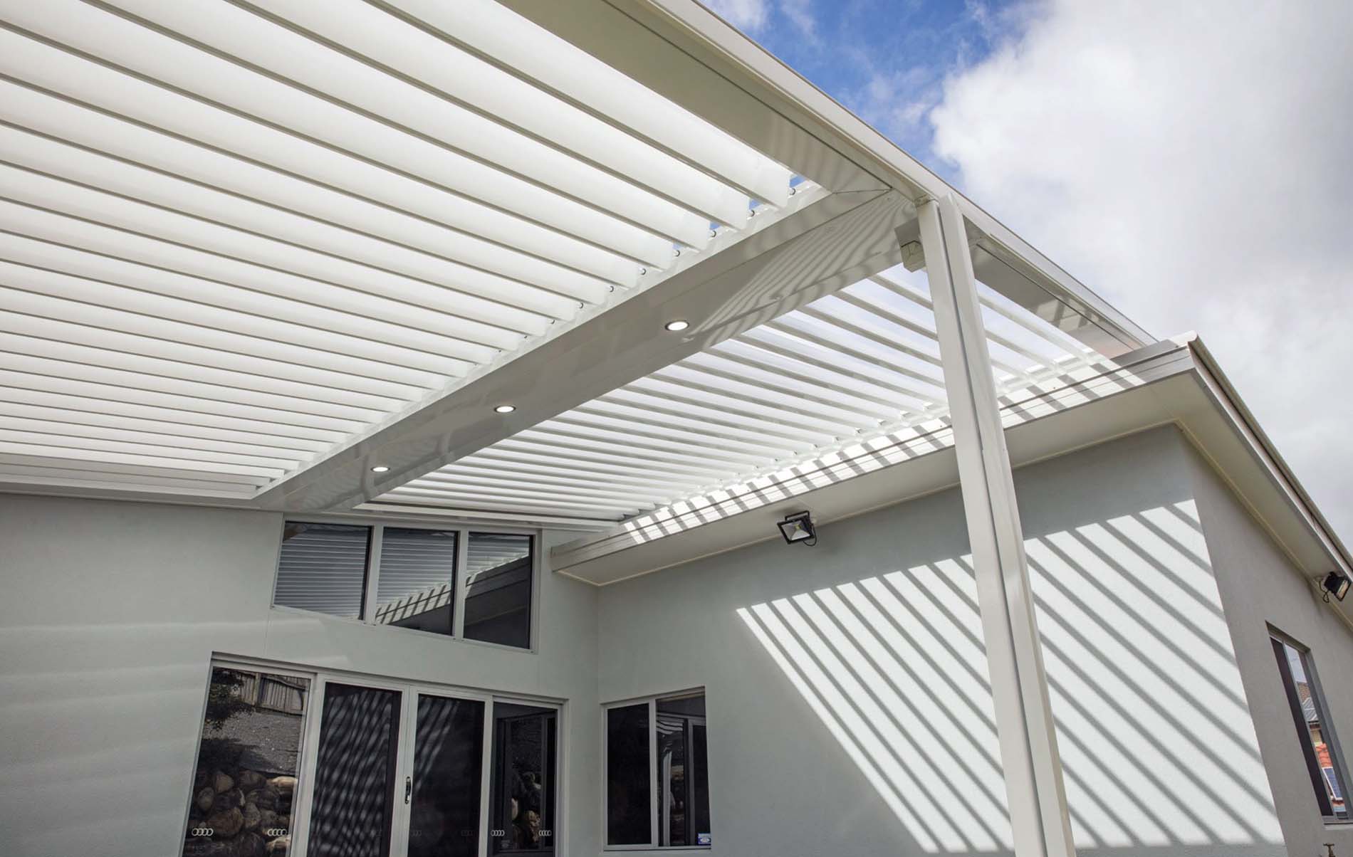 Contemporary outdoor patio with closed louvre roof and timber posts overlooking landscaped garden