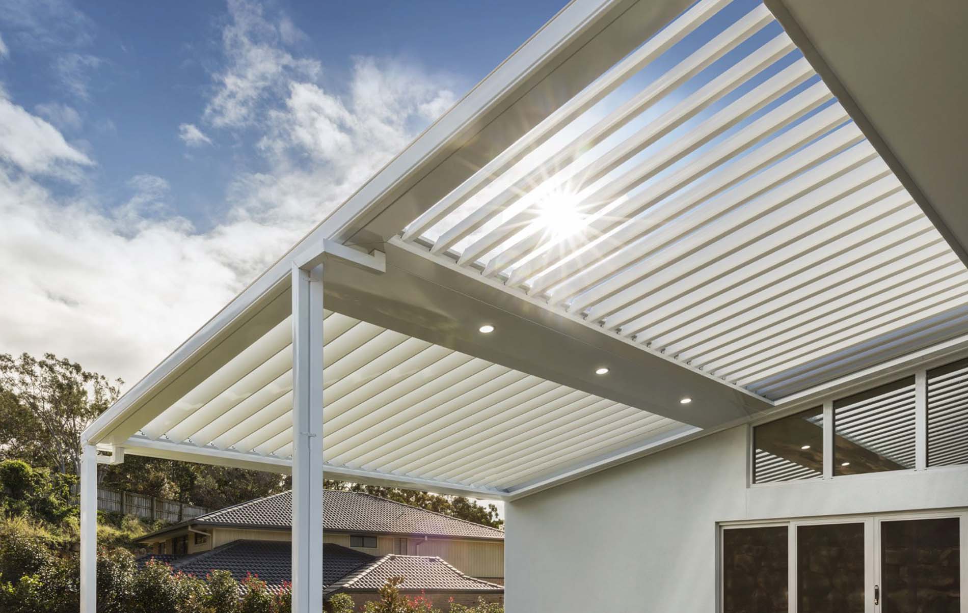 Contemporary outdoor space featuring louvre roof system with sleek white beams and modern stone paving