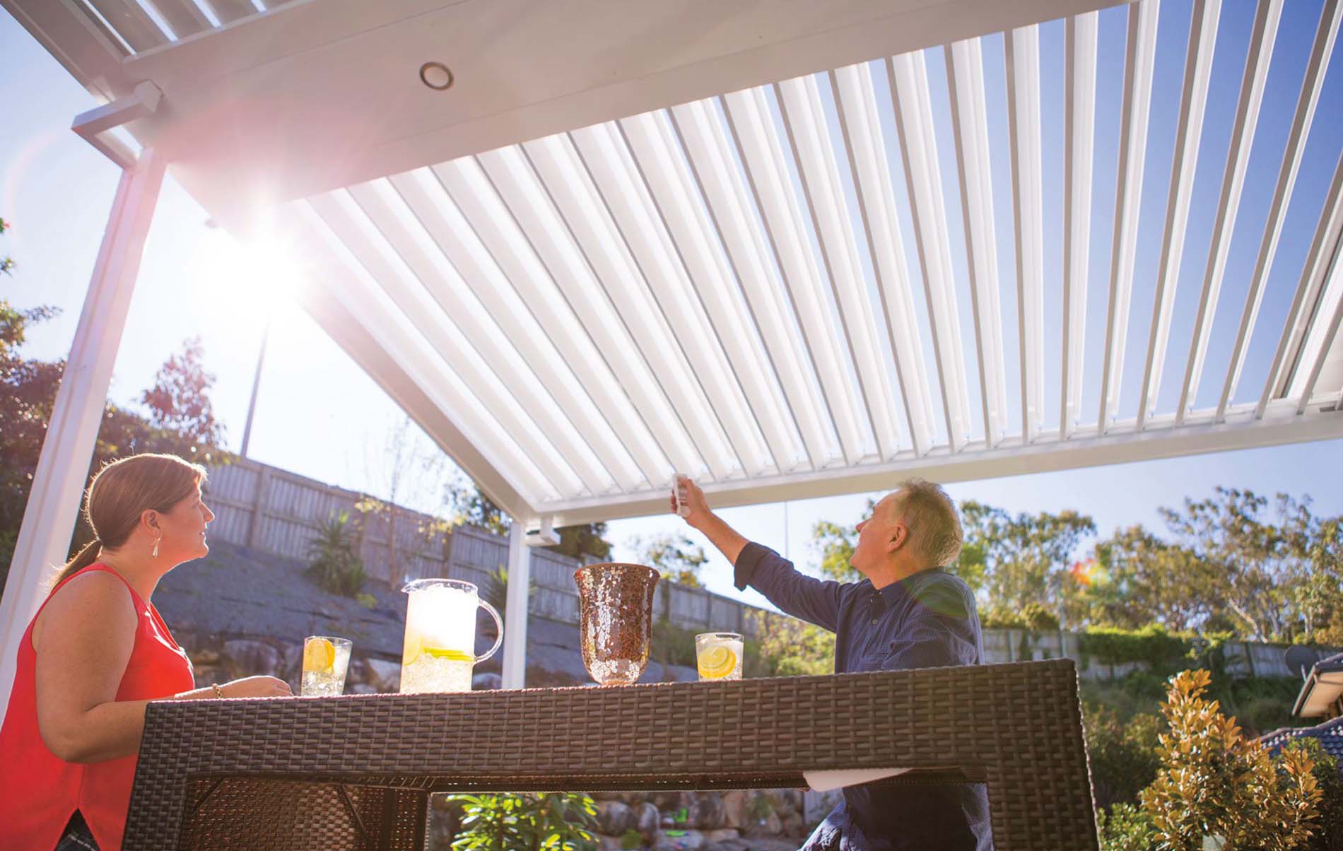 Wide outdoor louvre patio with fully open adjustable slats, timber posts, and garden landscaping