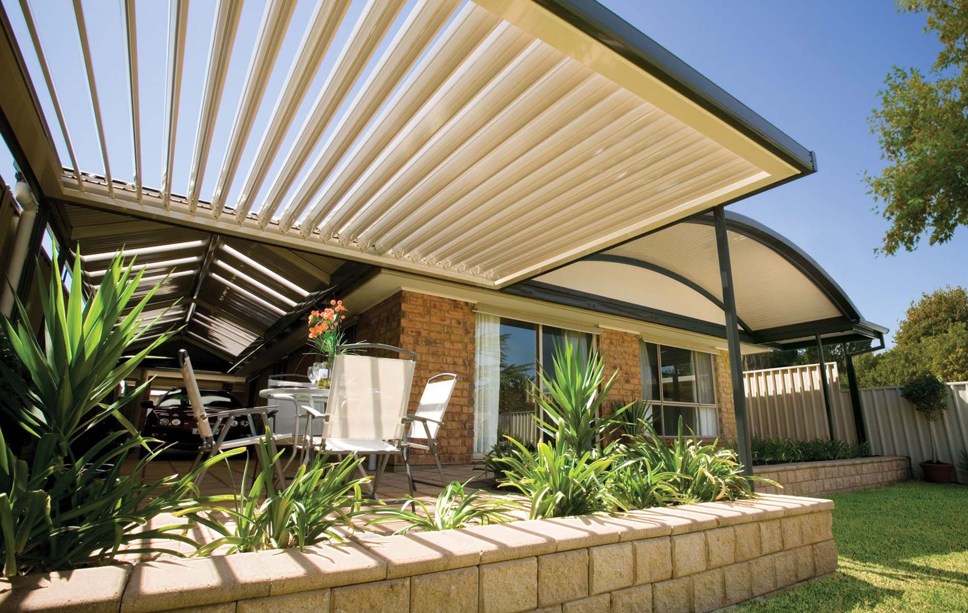 Outdoor lounge area under adjustable louvre roof with timber posts and garden view