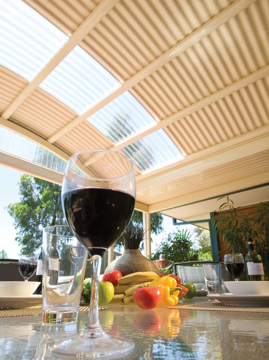 Portrait view of curved patio with dining table, wine glass, and fruit bowl