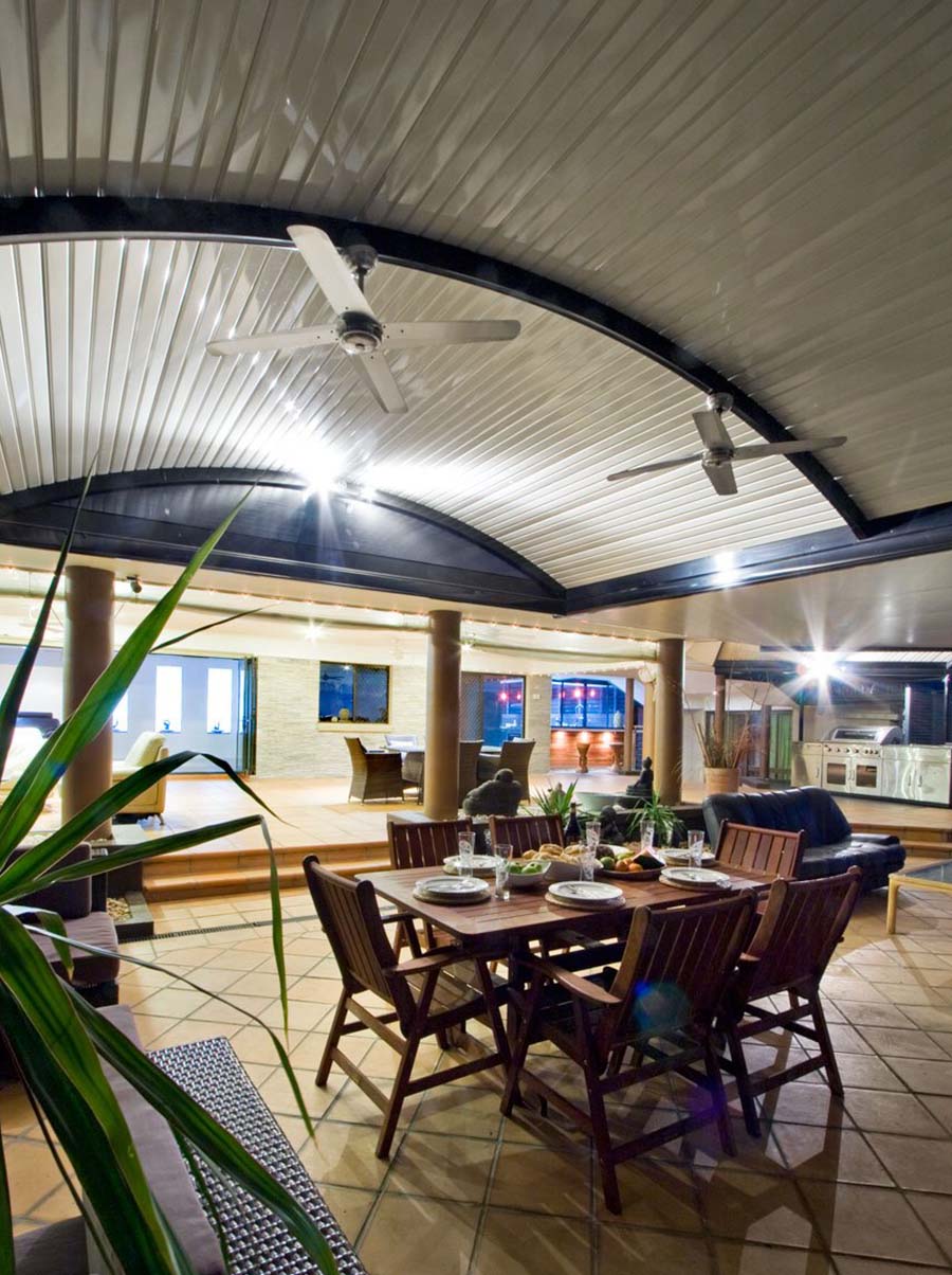 Side view of curved patio structure with timber-look posts and polycarbonate roof
