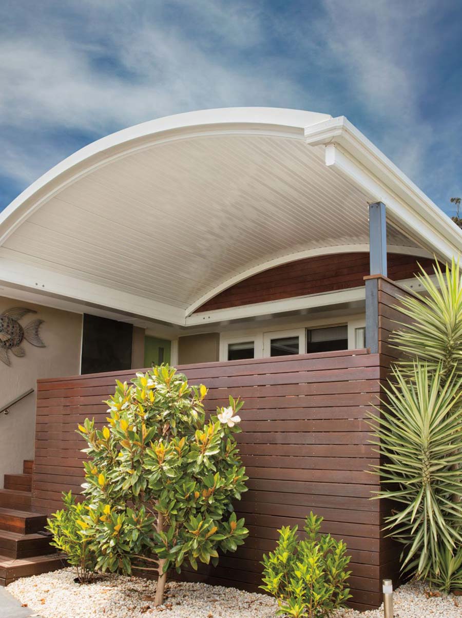 Outdoor setting under curved roof patio with dining table and timber posts